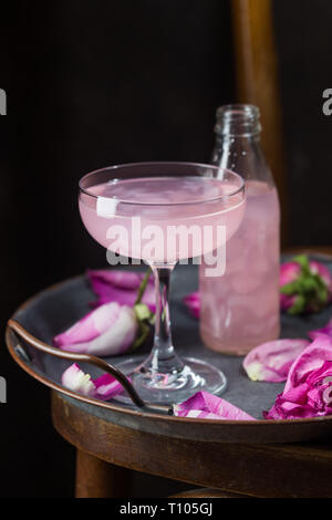 Summer refreshment drinks. Light pink rose cocktail, with rose wine on dark background. With rose flowers. Copy space Stock Photo