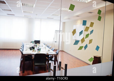 Blank colored sticky note or post note stuck on glass wall at office. Stock Photo