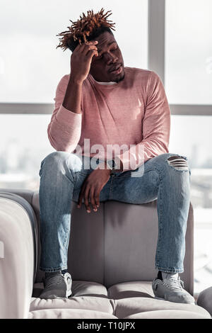 Serious bearded young man touching his forehead Stock Photo