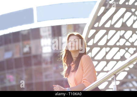 background image of a brooding business woman standing on the balcony of an office building Stock Photo