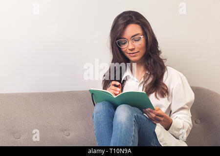 Portrait of a happy casual girl student writing in a notepad Stock Photo