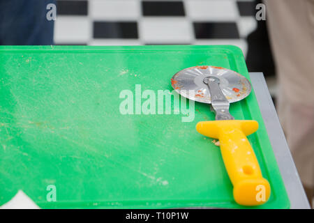 Pizza cutter on green desk. Stock Photo