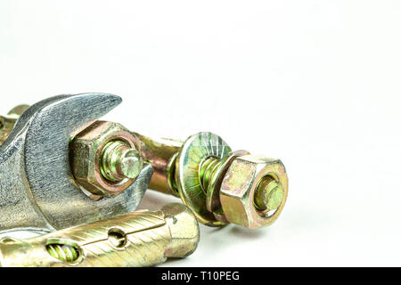 Close up steel expansion anchors bolts and wrench isolate on white background. Stock Photo