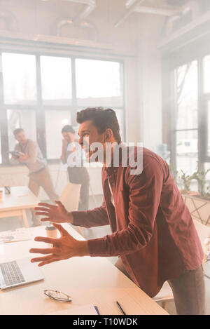terrified man having panic attack in office with smoke near coworkers Stock Photo