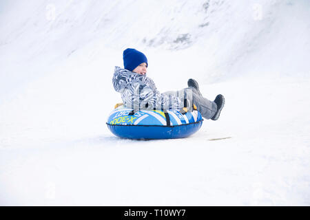 Belarus, the city of Gomel, January 07, 2018.Central Park.Child sledding cheesecake.Sledding off a snow slide.Ride on tubing. Winter children's holida Stock Photo