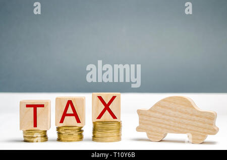 Wooden blocks with coins and the word Tax and wooden auto. The concept of growth taxes on cars. Taxes on the car are increasing. The accumulation of m Stock Photo