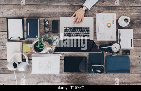 Mix of office supplies and gadgets on a wooden desk Stock Photo