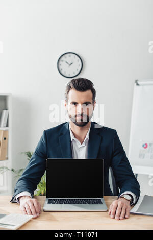 handsome advisor in suit showing laptop with copy space Stock Photo