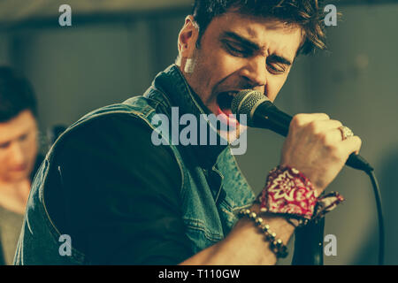 selective focus of handsome stylish man singing in microphone Stock Photo