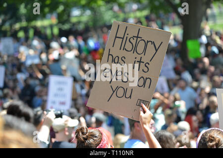 Woman holding homemade sign at political rally, colorful crowd in background Stock Photo