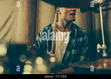 cropped view of man singing in microphone while playing drums Stock Photo