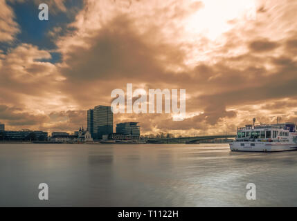 Long Exposure of the River Rhine, a colorful glowing Sky, Ships and a modern Skylines at High Water Level in Cologne Germany in 2019. Stock Photo