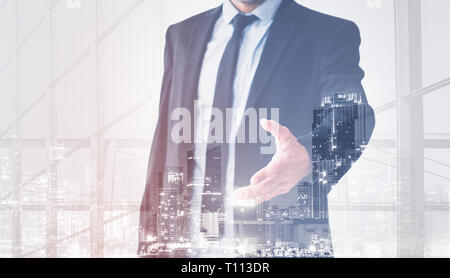 businessman shaking hands, man in suit offering hand for handshake, skyline double exposure Stock Photo