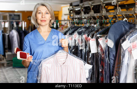 Portrait of diligent positive cheerful female laundry worker at her workplace Stock Photo