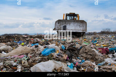 Bulldozer working on mountain of garbage in landfill Stock Photo