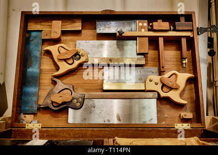 Traditional woodworking hand saws and carpentry tools in a cabinet Stock Photo
