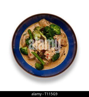 A blue bowl of succulent Thai Red Chicken Curry isolated on a white background with a drop shadow. Stock Photo