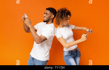 Excited young man and woman playing together on smartphones Stock Photo