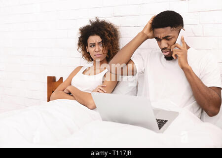 African-american guy working in bed and ignoring his wife Stock Photo