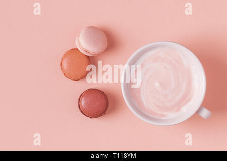 Cup of coffee with macaroons on pastel background, flat lay. Stock Photo