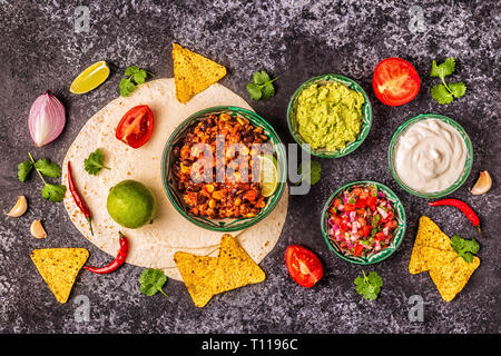 Mexican food concept: tortillas, nachos with guacamole, salsa, chili con carne, top view. Stock Photo