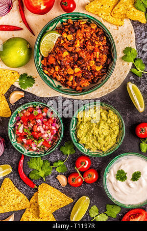 Mexican food concept: tortillas, nachos with guacamole, salsa, chili con carne, top view. Stock Photo