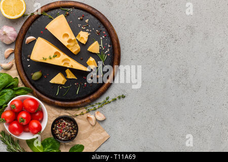 Cheese, tomatoes and fresh herbs on concrete background. Stock Photo