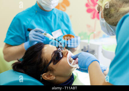 Smiling pretty woman is having her teeth examined by dentist in clinic. Concept of caries treatment Stock Photo