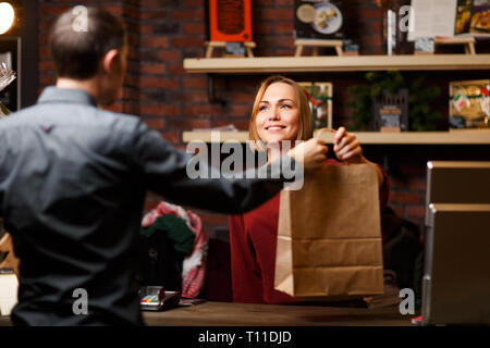 Picture of girl seller with paper bag and man shopper from back Stock Photo