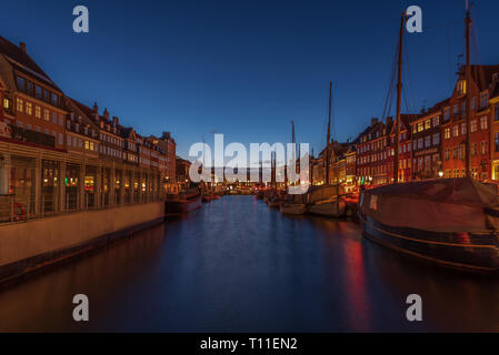 Early evening lights on the Nyhavn canal in Copenhagen, boats and night reflections Stock Photo