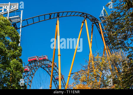 A rollercoaster and the world famous Weiner Riesenrad giant Ferris wheel of Prater Park in Vienna. Prater Park is home to the world’s oldest amusement Stock Photo