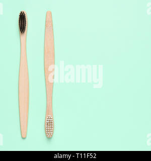 Bamboo toothbrushes on light green background with text space Stock Photo