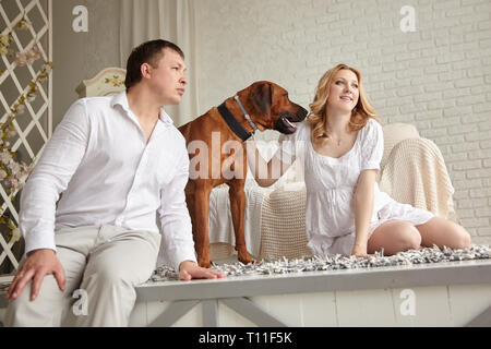 happy young couple with their pet sitting on the living room floor. Stock Photo
