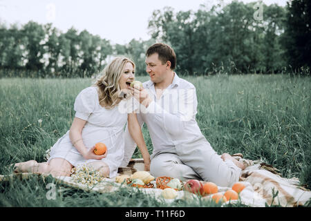 happy man with his pregnant wife at picnic on summer day Stock Photo