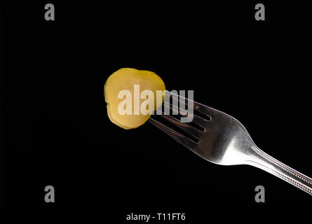 Slice of pickled cucumber on fork isolated on a black background. Copy space. Stock Photo