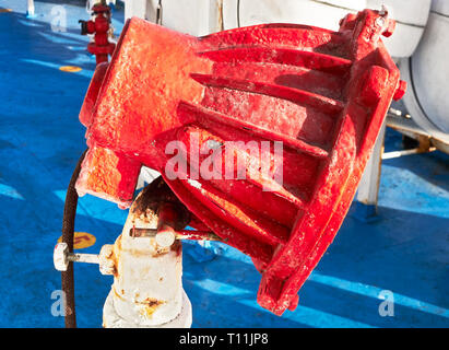 Close-up of a rusty red color painted flood light against a blue floor on deck of a ship in Asia Stock Photo