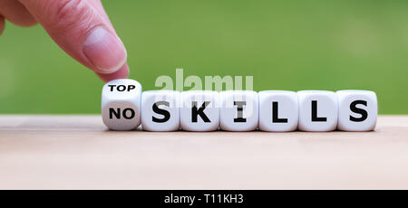 Hand turns a dice and changes the expression 'no skills' to 'top skills'. Stock Photo