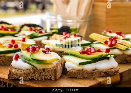 Avocado Sandwich with Feta cheese - sliced avocado and Feta cheese on bread with arugula leaves, embellished with pomegranate pips and sesame seeds fo Stock Photo