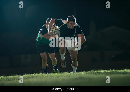 Flanker running with ball and tackling opponents during game. Rugby match in action. Stock Photo