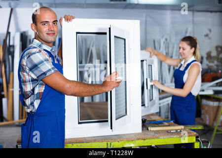 Diligent efficient  confident man in workwear with finished window from pvc profile at workplace Stock Photo