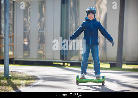 Happy boy riding on self-balancing deck in city park Stock Photo