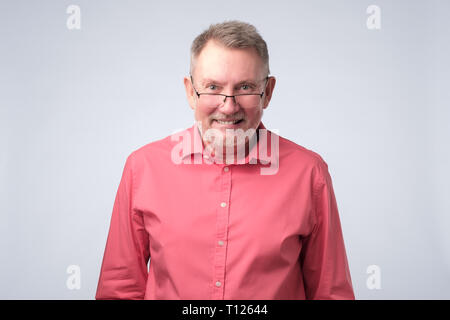 Serious man in red shirt wearing glasses smiling confident. Positive facial emotion Stock Photo