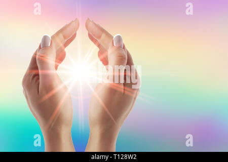 Healing hands with bright sunburst on rainbow background Stock Photo