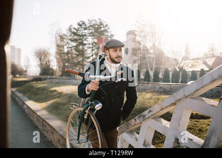 Old fashioned bicycle rider with bike on his shoulder Stock Photo