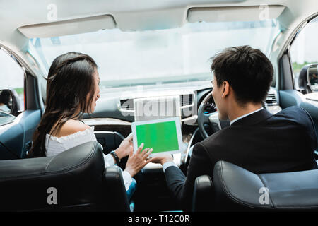 two couple using tablet together while driving a car Stock Photo