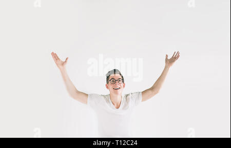 Young happy man with in casuals with raised hands up isolated on white background. Nerd is wearing glasses Stock Photo