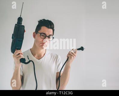 Funny portrait upset craftsmen. Nerd is wearing glasses.. Does not know how to use a drill. Stock Photo
