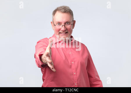 Handsome senior man in red shirt saying hello Stock Photo