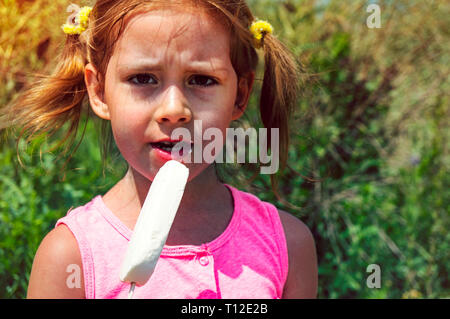 Child eating ice cream. Kids play outdoors enjoying sweet snack on a hot summer day. Children eat icecream. Toddler kid playing in the garden. Little  Stock Photo