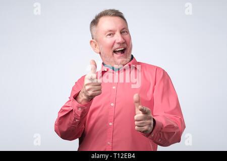 Senior man in red shirt pointing fingers at you Stock Photo